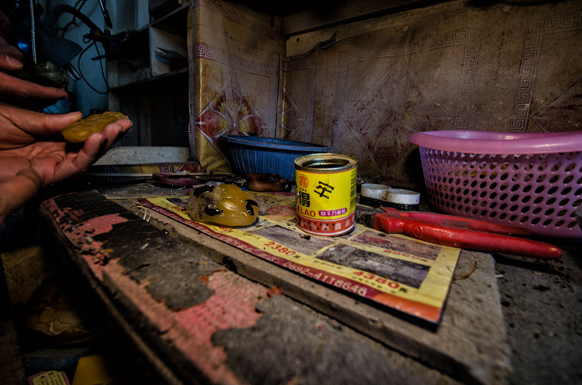 Applying a reddish varnish to the surface of a jade-like material in a workshop in Ruili's jade market. Following the treatment, which probably involves firing in an oven, the treated portions assume a reddish color that simulates the natural oxidation staining on the surface of jade boulders. Lotus Gemology looks at jade, jade treatments, nephrite.