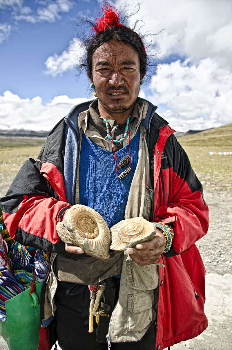 Ancient wisdom Tibetan man offering fossils for sale atop, Tropou La (4500 m; 14,763 ft). Before the collision with the Indian subcontinent, Tibet was a sea, and marine fossils are thus found throughout the land.&nbsp;Photo: Richard W. Hughes