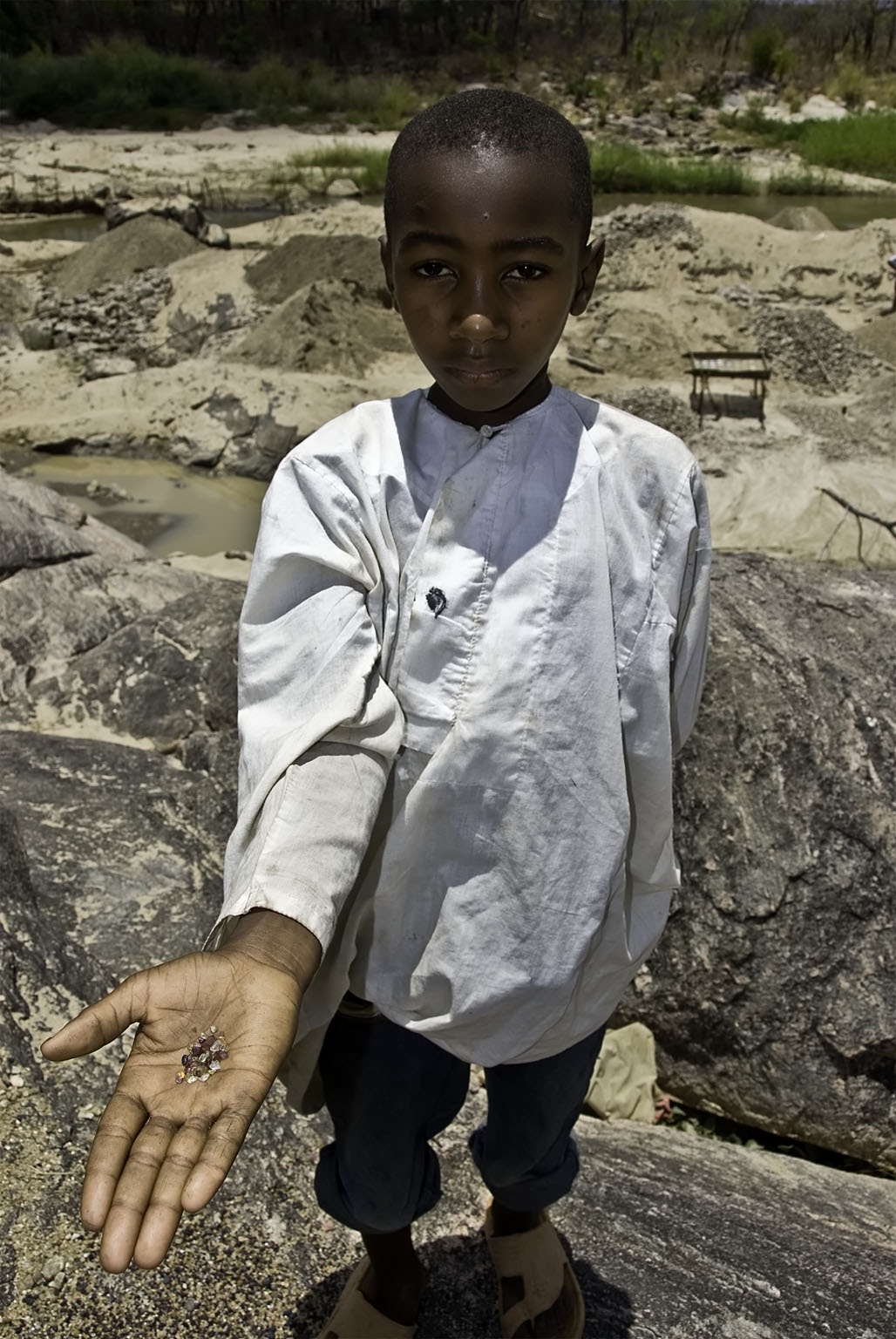 A young boy along the Muhuwesi River with a handful of gems.