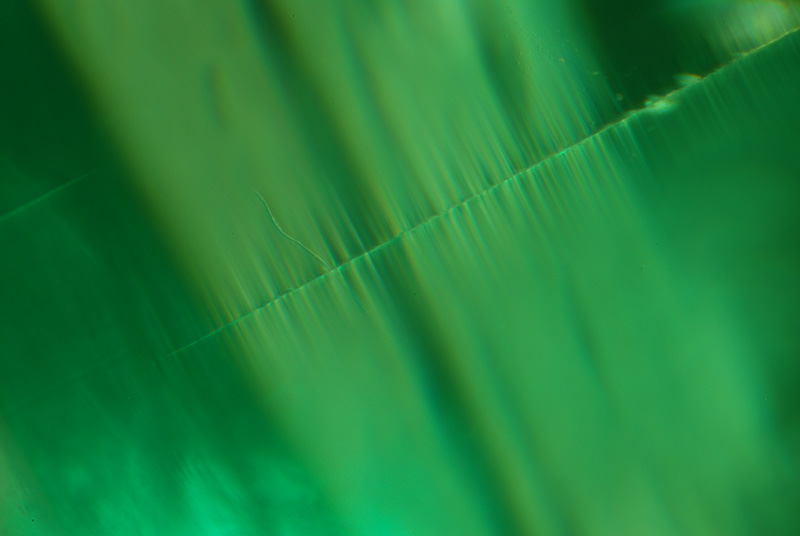 Top:&nbsp;Two-phase thin films seen in both reflected and transmitted light on the basal plane of an emerald from Malysheva, Russia. Below: The same thin films as seen looking parallel to the basal pinacoid.&nbsp;Specimen courtesy of Tsar Emeralds Corp.; photomicrographs © John I. Koivula/microWorld of Gems