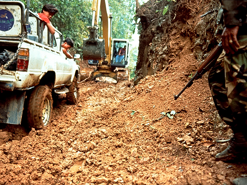 Utilizing its mechanical arm, a backhoe drags our truck out of Hweka