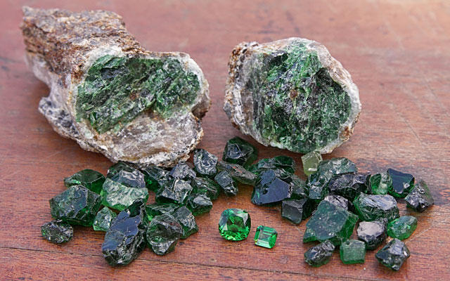 Tsavorite porphyroblast, along with rough and faceted gems from Tsavo area, Kenya. Stones courtesy: Genson Micheni Musa/ Tsavolite Co Ltd, Photo: V. Pardieu/Gübelin Gem Lab, 2007.
